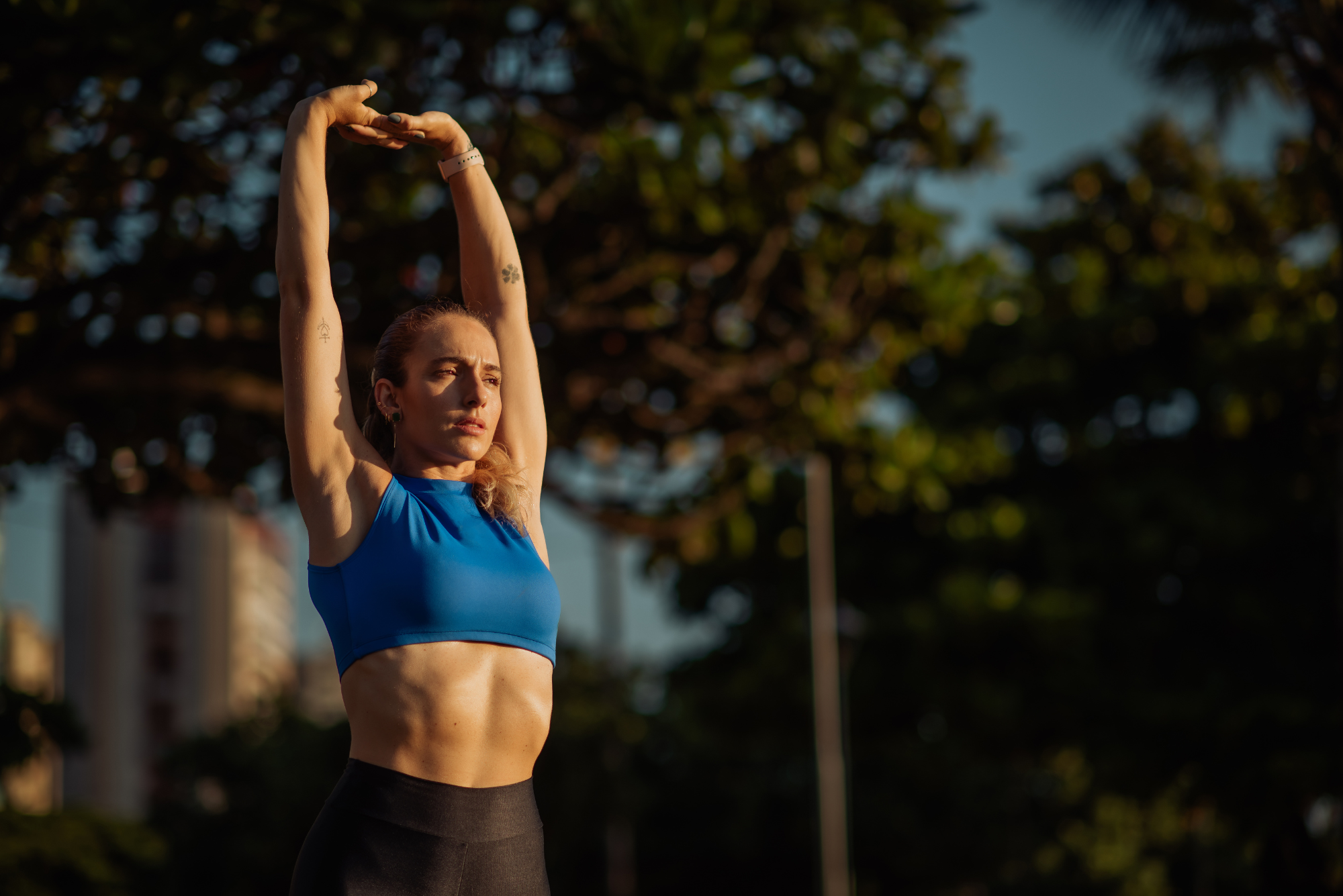 Athletic woman stretching outdoors in sunlight, promoting the benefits of physical activity and regular movement for health.