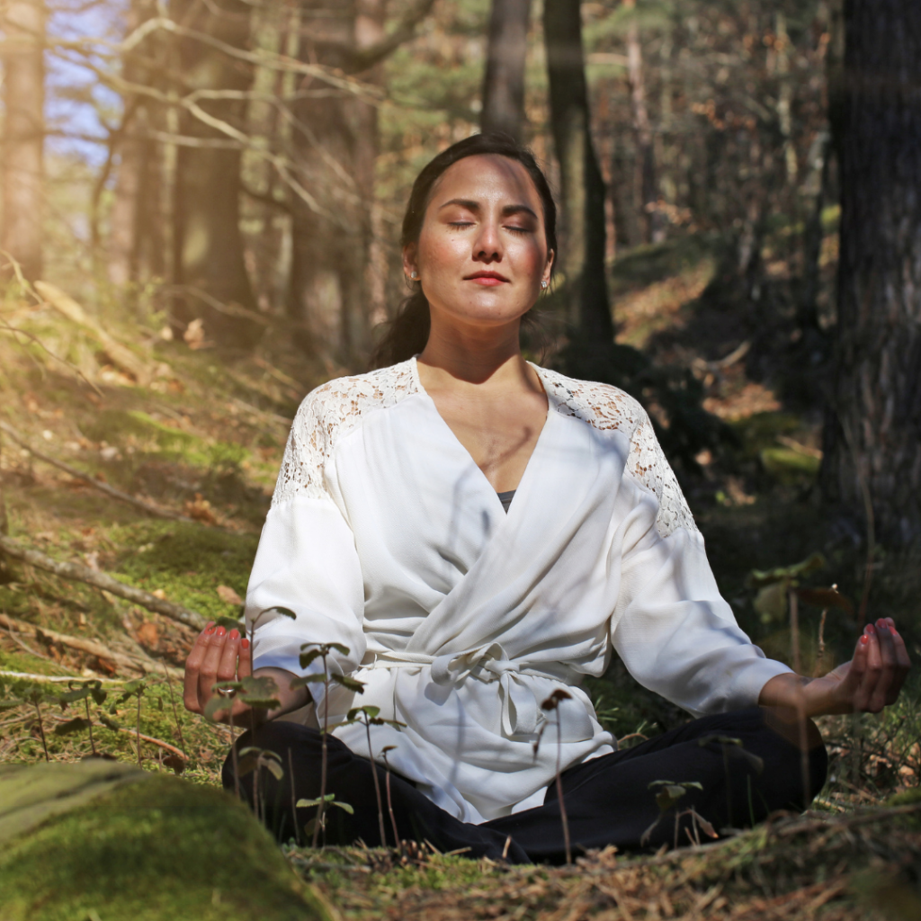 A person meditating in a forest setting.